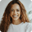 Smiling woman with curly hair wearing a white top.