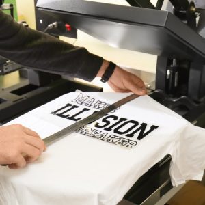 Person printing a custom design on a white T-shirt using a heat press machine.