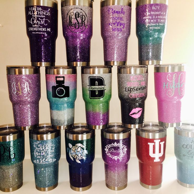 A collection of colorful, glittery tumblers with various logos and designs.