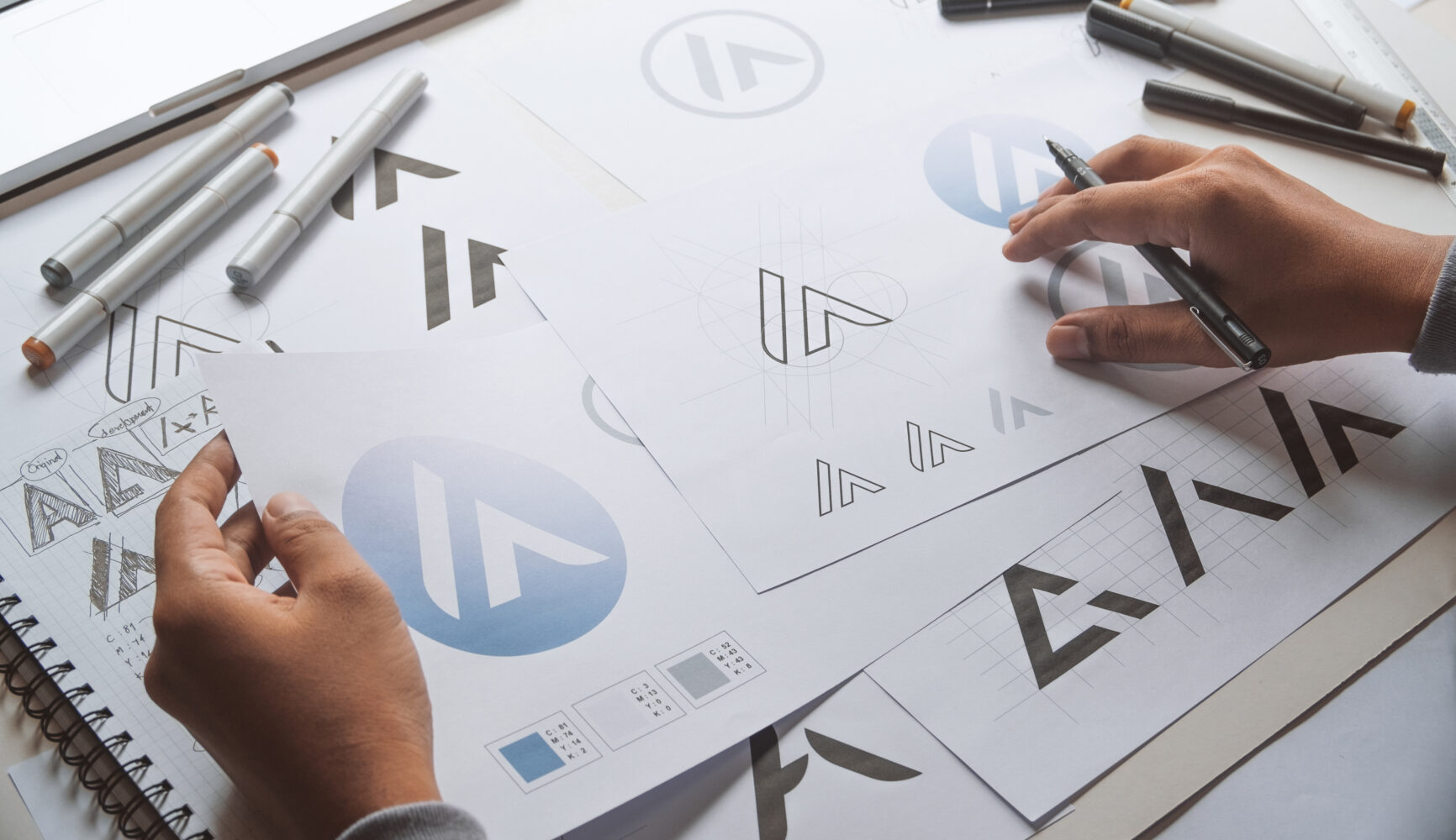 Hands sketching and designing modern logos on paper.